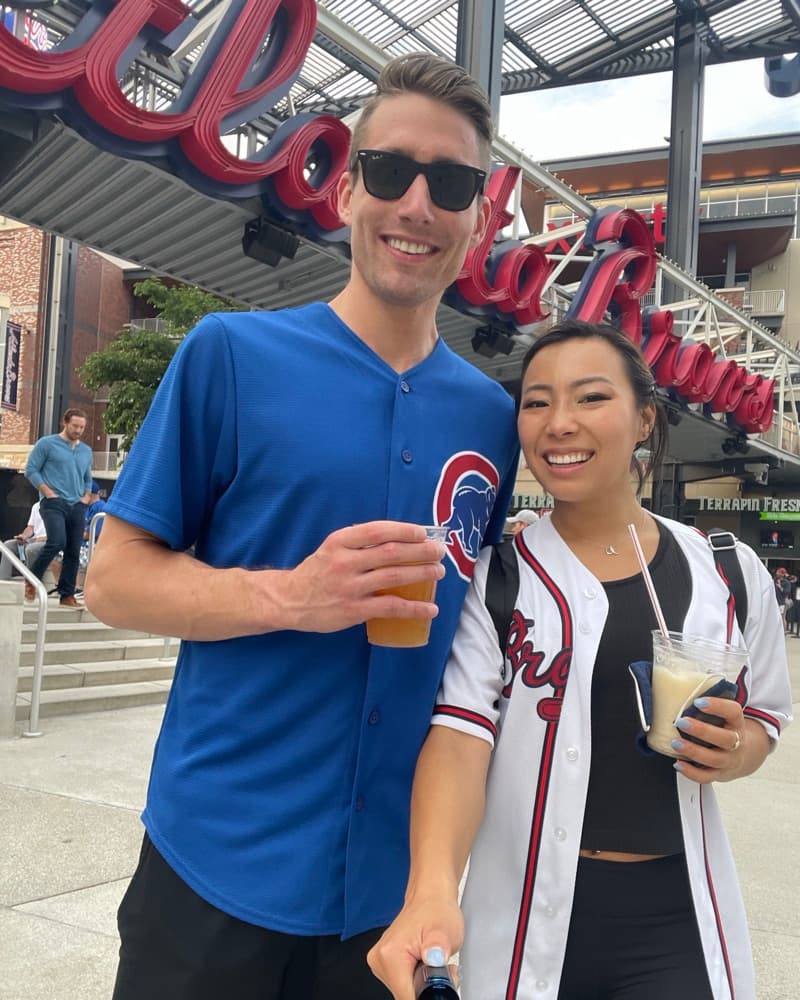 Matt in a Cubs jersey and Anna in a Braves jersey outside the Braves' ballpark.