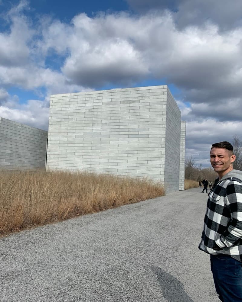 Matt beside huge stone cubes in a meadow at Glenstone.