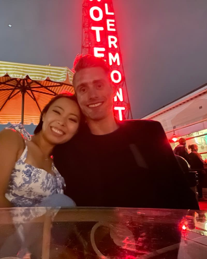 Anna and Matt at night on a rooftop under the red Hotel Clermont sign.