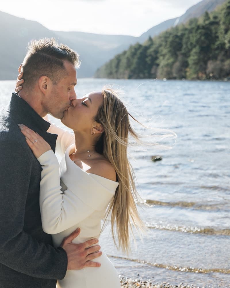 Matt and Anna kissing on the shore of the lake at Glendalough.
